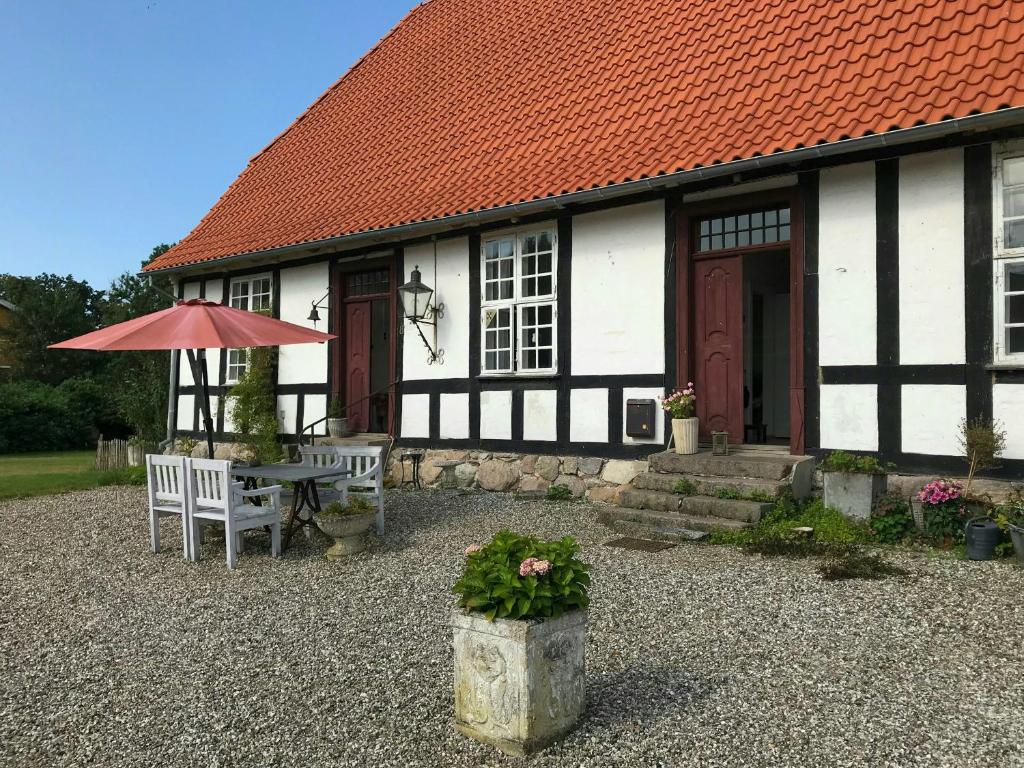 Historic Manor House At Gelskov Estate في Sandholts-Lyndelse: مبنى ابيض واسود مع طاولة ومظلة