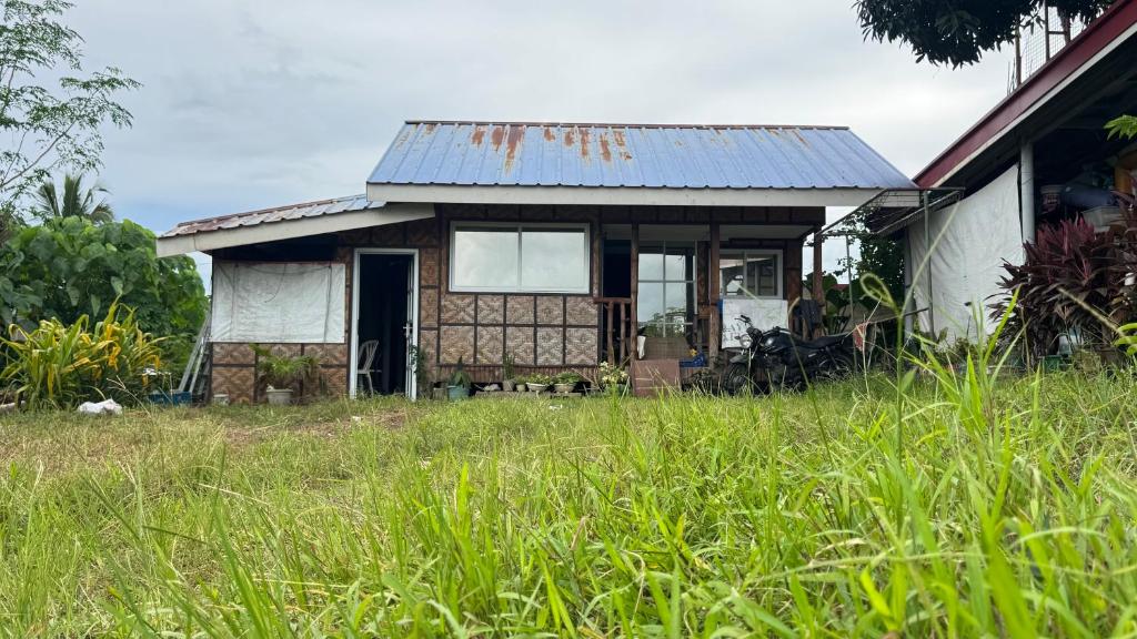 an old house in a field of grass at TeamV Kubo Guesthouse in Agdañgan
