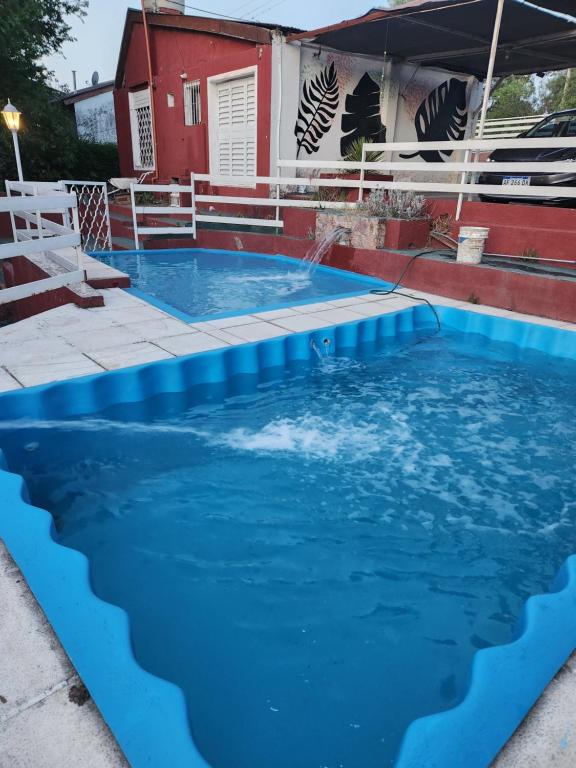 a pool with blue water in front of a house at Altos de Grecia Cabaña 1 in Villa Carlos Paz