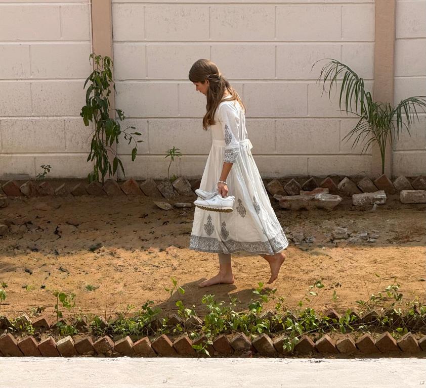 una niña con un vestido blanco caminando por la calle en Hotel Jaipur In, Jatipura Parikrama Marg Near Mukharvind Temple, en Govardhan