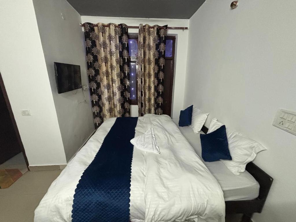 Un dormitorio con una cama con sábanas azules y blancas y una ventana. en Hotel R Villa - Near Hauz Khas Fort, en Nueva Delhi