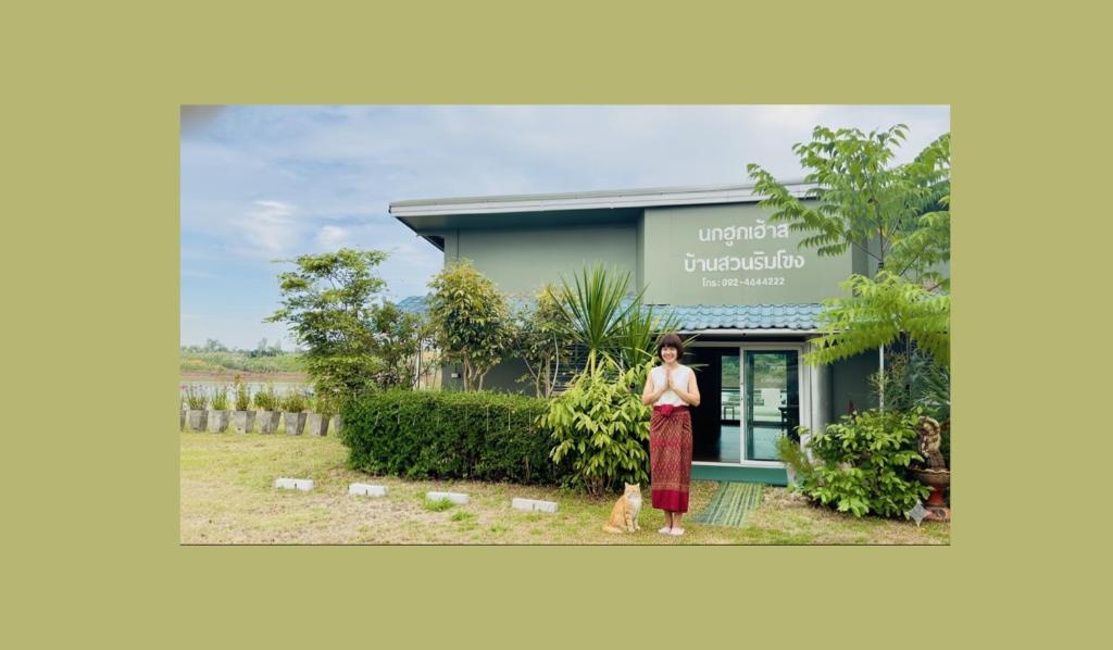 a woman standing in front of a house at นกฮูกเฮ้าส์ ริมโขง in Nong Khai
