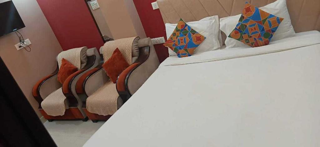 two beds with pillows and chairs in a room at Hotel O The Buddha Residency in Dānāpur