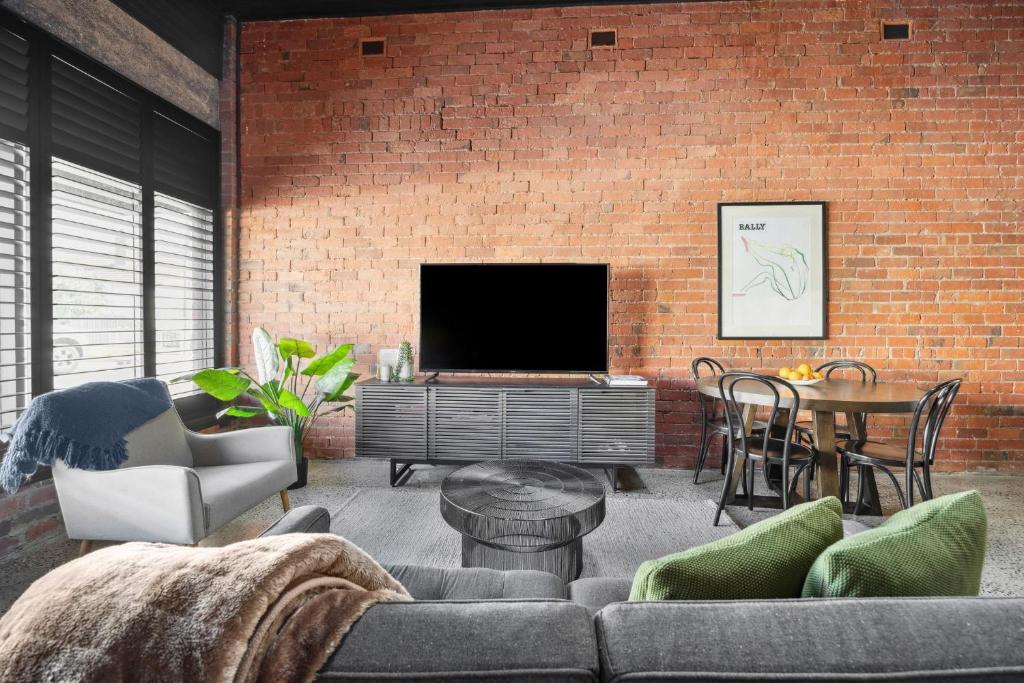 a living room with a brick wall and a tv at The Milliner - Boutique Living, Geelong West in Geelong West