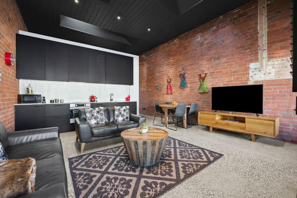 The Radford on Elizabeth في Geelong West: غرفة معيشة فيها تلفزيون وجدار من الطوب