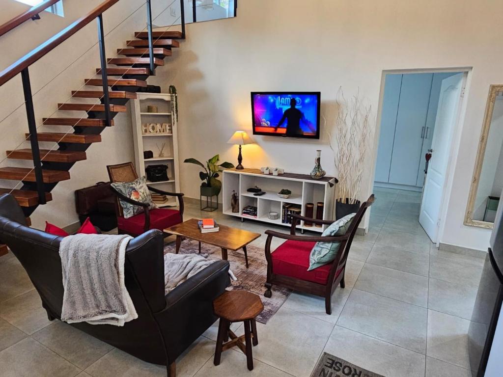 a living room with a couch and chairs and a staircase at ONE on Michelle in Ballito