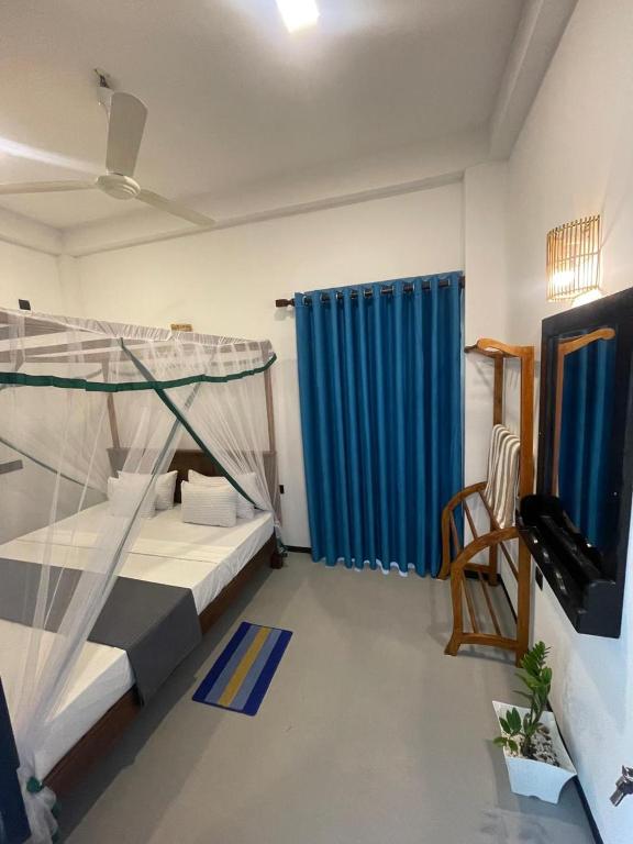 a bedroom with a bunk bed and a blue curtain at Adorable Guest House in Midigama East