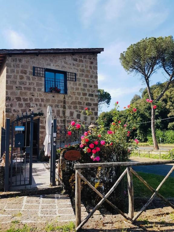 a stone house with a gate and flowers at Le Terrecotte Sutri in Sutri