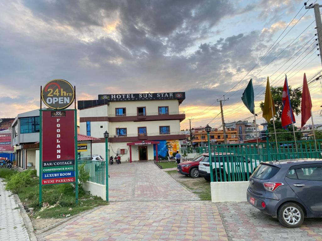a hotel sign in front of a building with parked cars at Hotel Sun Star International Pvt Ltd in Bhairāhawā