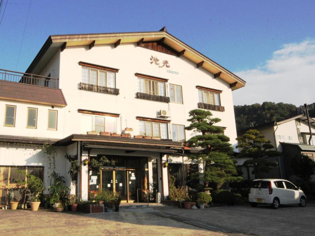 un edificio blanco con un coche aparcado delante de él en Ikemoto, en Nozawa Onsen