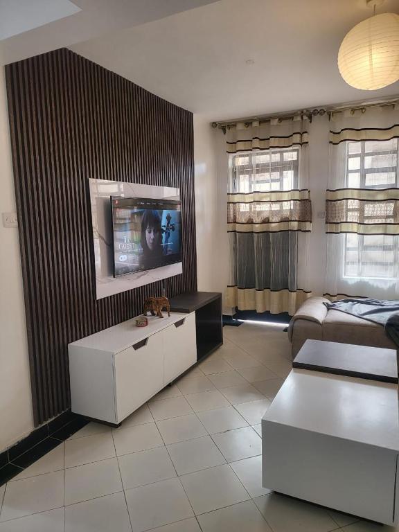 a living room with a tv and a couch at Kim's Executive Three bedroom apartment with outdoor, Nakuru CBD in Nakuru
