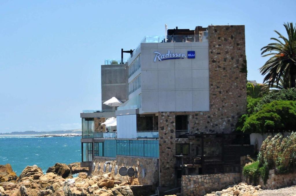 a building with a sign on it next to the ocean at Radisson Blu Acqua Hotel & Spa Concon in Concón