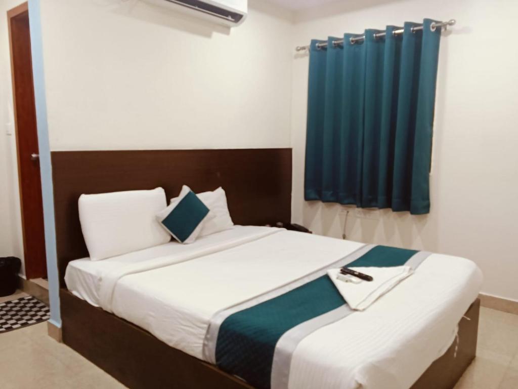 a bedroom with a bed with a blue curtain at At Home Hotel Darbar in Hyderabad