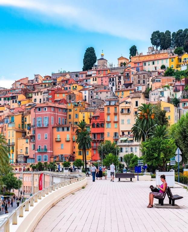 a woman sitting on a bench in front of a city at Bright apartment in Menton in Menton