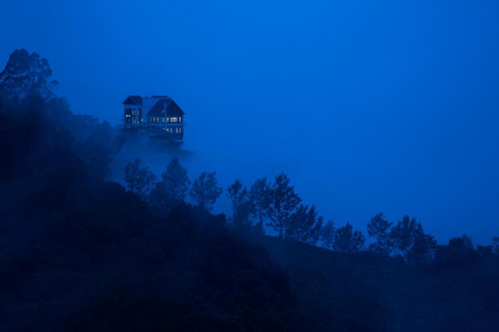 a house on top of a hill in the fog at Fragrant Nature Munnar - A Five Star Classified Hotel in Munnar
