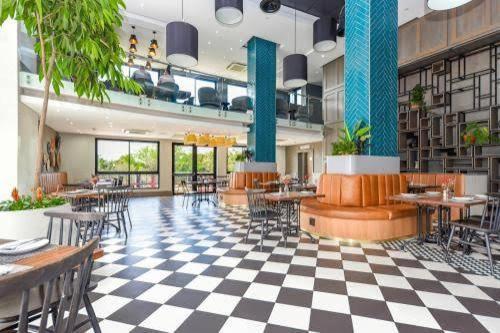 a restaurant with tables and chairs and a checkered floor at Cosy Regency menylin apartment in Pretoria