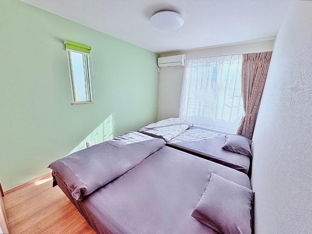 a bed with purple sheets in a room with a window at Hotel Sakura 宇都宮 in Utsunomiya
