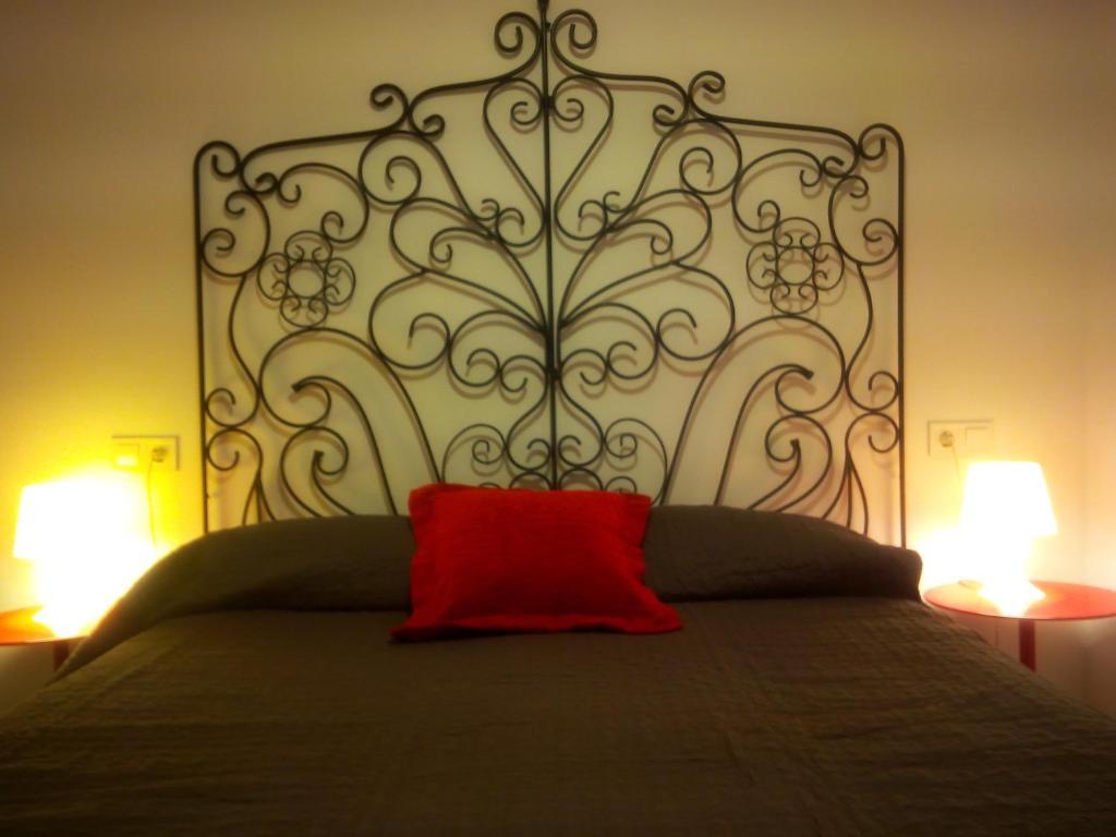 almohada roja en la parte superior de una cama con 2 lámparas en Bnap Masip, en Oviedo