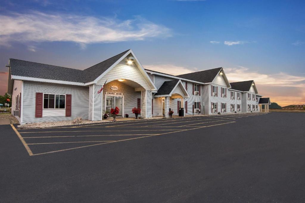 a large white building with a parking lot at Baymont by Wyndham Marinette in Marinette