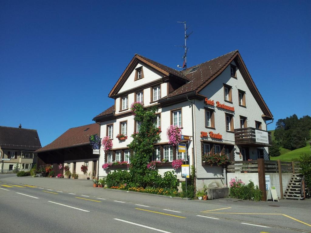 uma casa branca com flores ao lado de uma rua em Hotel Garni Traube B&B em Schwellbrunn