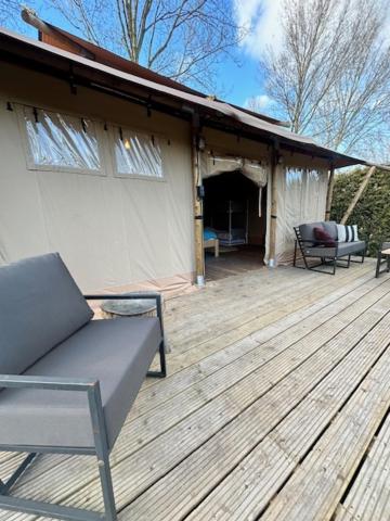 a wooden deck with a chair and a house at Safari Lodge at Back to Basic in Zwaanshoek