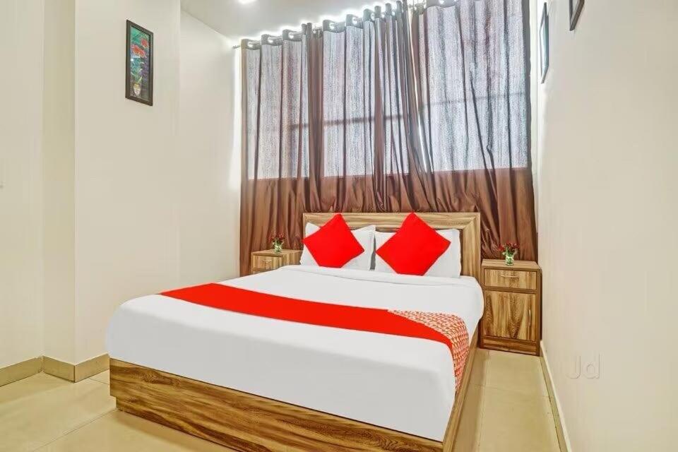 Un dormitorio con una cama grande con almohadas rojas. en Collection O Kammasandra Gate Bus Terminal Formerly Riches Inn, en Bayappanhalli