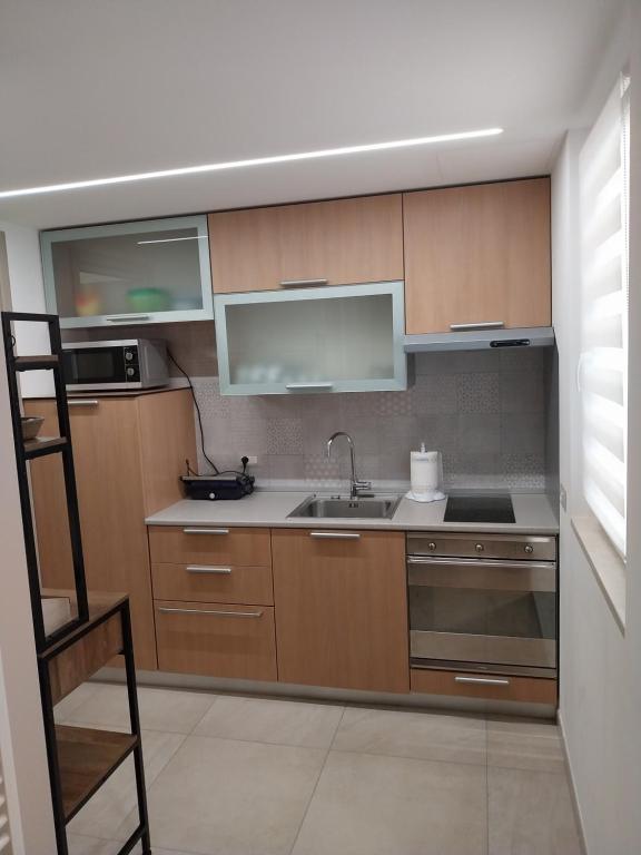 eine Küche mit Holzschränken, Spüle und Mikrowelle in der Unterkunft Relais Frantoio delle Pietre in Conversano