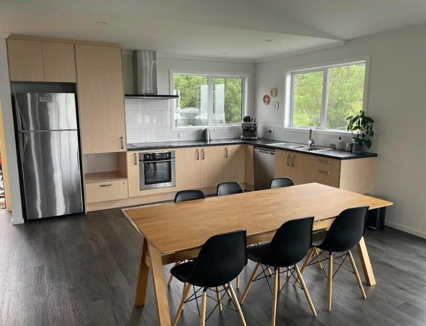 a kitchen with a wooden table and chairs at Bay Vista - glorious Golden Bay Ocean Views in Pohara