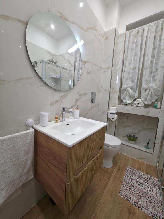 a bathroom with a sink and a mirror and a toilet at Maison Luisa in Pozzuoli