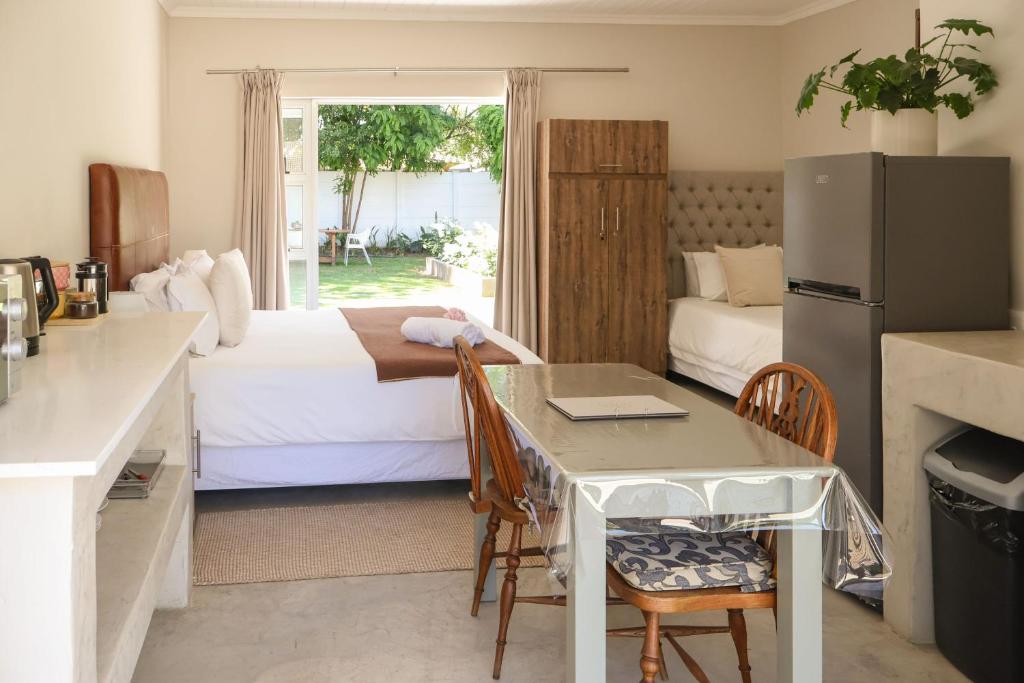 a kitchen with a table and a refrigerator in a room at Villa Vredenrust Guesthouse in Bloemfontein