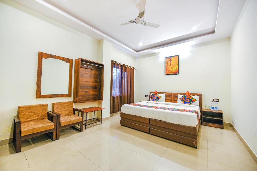 a bedroom with a bed and a chair and a mirror at Hotel Alaknanda Paradise in Dehradun
