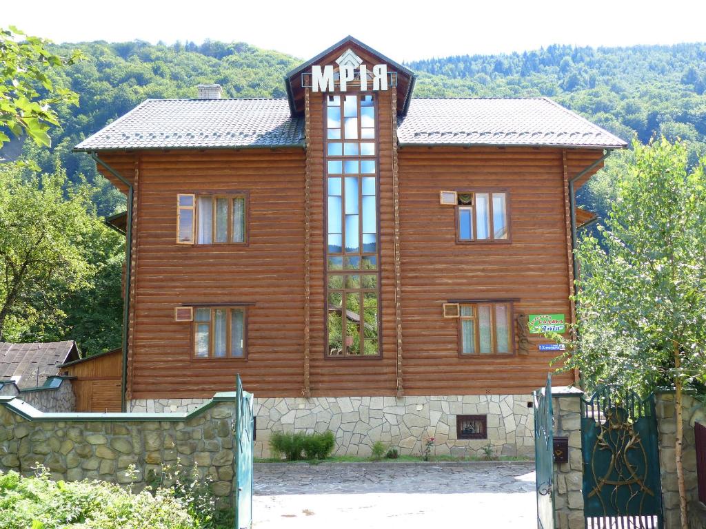 a large wooden house with a stone wall at Mrija in Yaremche