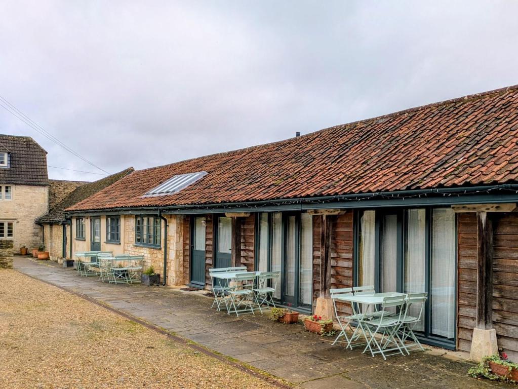 RudloeにあるLower Rudloe Farmの外にテーブルと椅子が置かれた一列の家