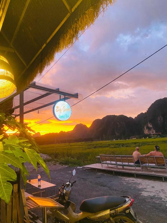 two men sitting on a bench watching the sunset at Big J gest house in Ninh Binh