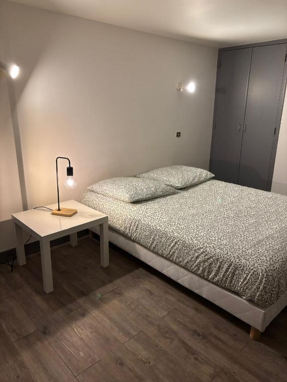 a bedroom with a bed and a table with a lamp at Le Nid du Sablard in Limoges