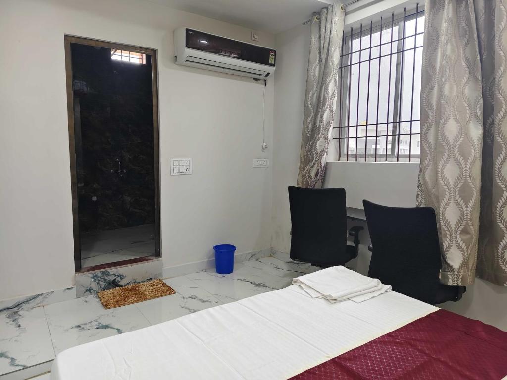 ビラースプルにあるHotel O Luxelineのベッド1台、椅子2脚、窓が備わる客室です。