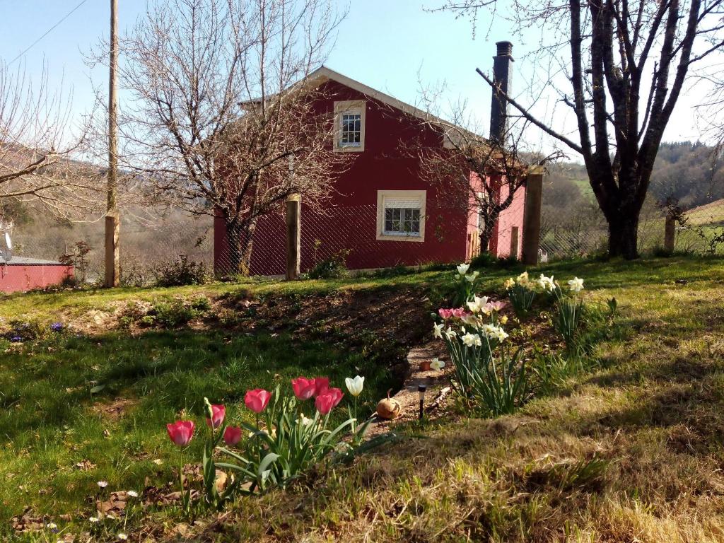 una casa roja con flores en el césped en Casa do Xastre, en Baralla