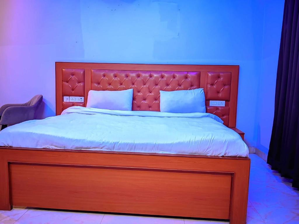 a bedroom with a large wooden bed with a red headboard at Hotel O Lavish Hotel in Greater Noida