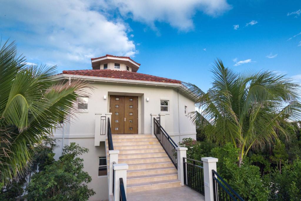 a white house with a wooden door and stairs at Karana Penthouse - K4 in Providenciales