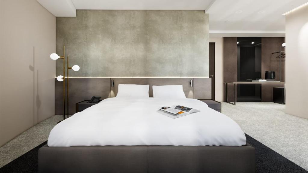 una camera da letto con un letto bianco e una rivista sopra di SUPERB HoTEL a Magong