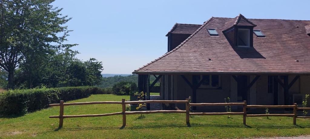 a small house with a wooden fence in the grass at Le Champêtre in Vézac