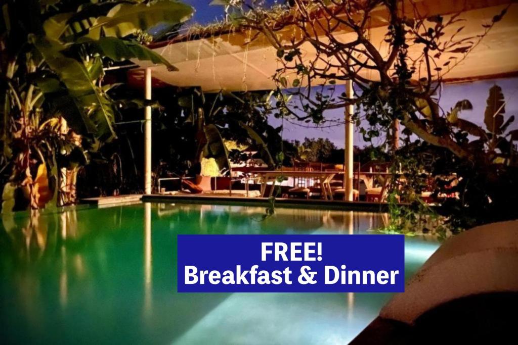 a swimming pool with the words free breakfast and dinner on it at The Hide Hostel Canggu - Adult Only in Canggu