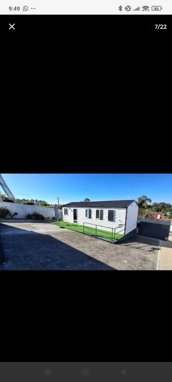 a white building with a green stripe next to a road at Fantastic house in Aldeia Nova