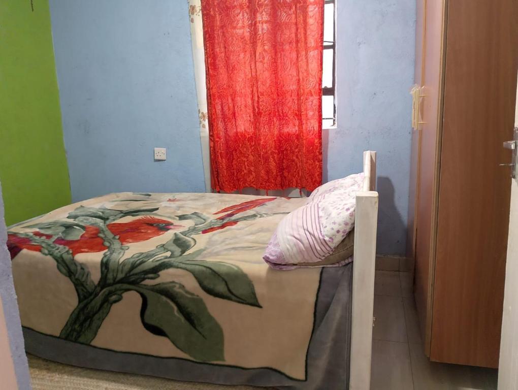 a bed in a room with a red curtain at Sacred Heart Apartments BNB & Hostels Meru Town in Meru