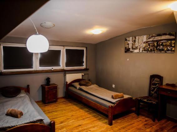 a bedroom with a bed and a chair and windows at Hotels Widok Rynek Centrum-fvat in Kielce