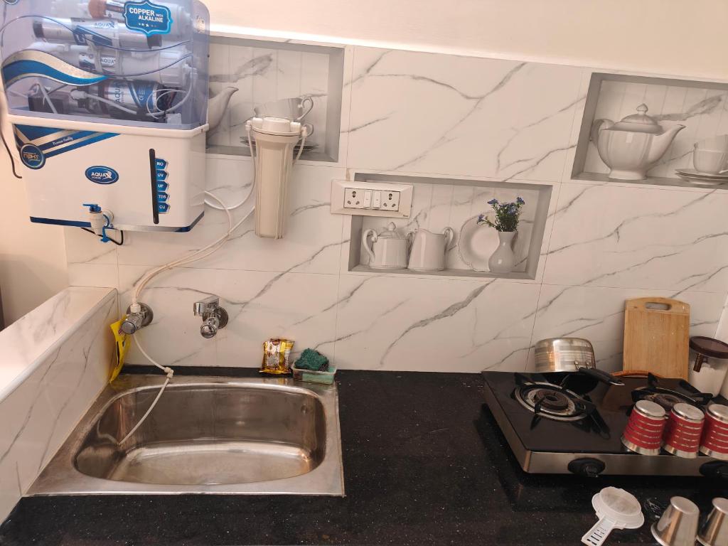 a small kitchen with a sink and a stove at Buddha Home stay in Mahabalipuram