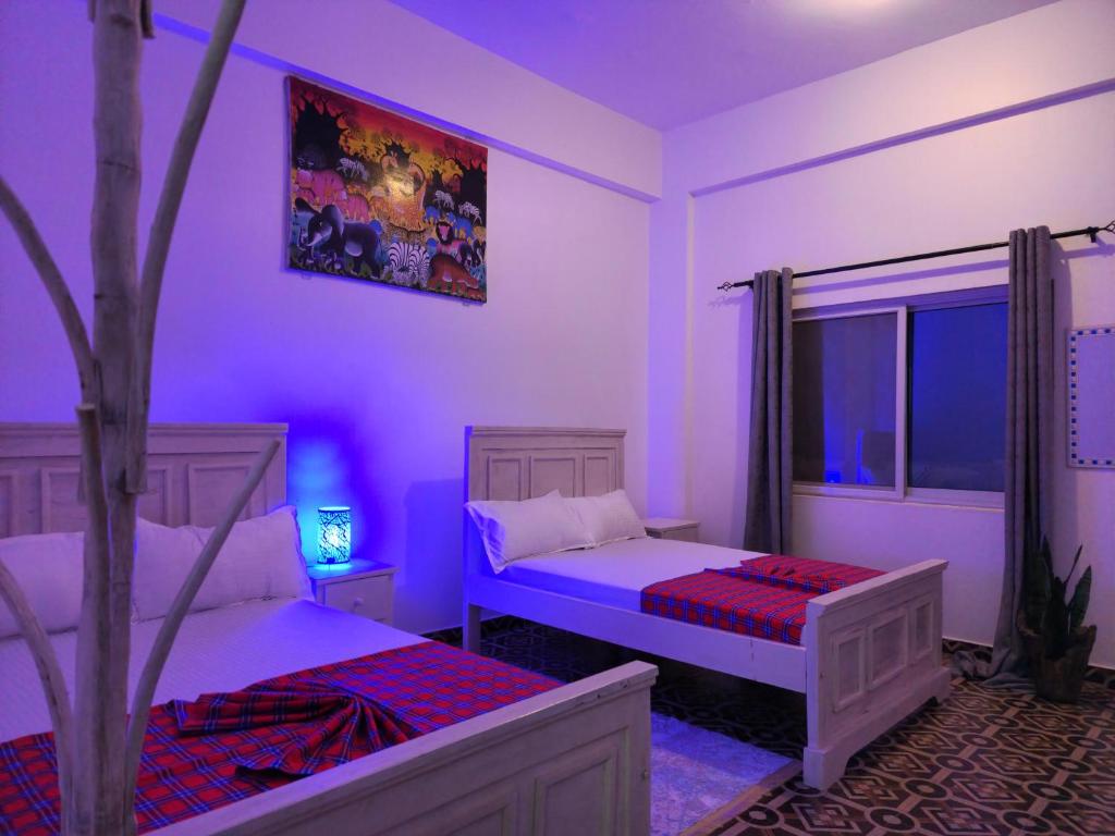 Un dormitorio con dos camas y un árbol dentro. en SeaRenityHomesWatamu, en Watamu