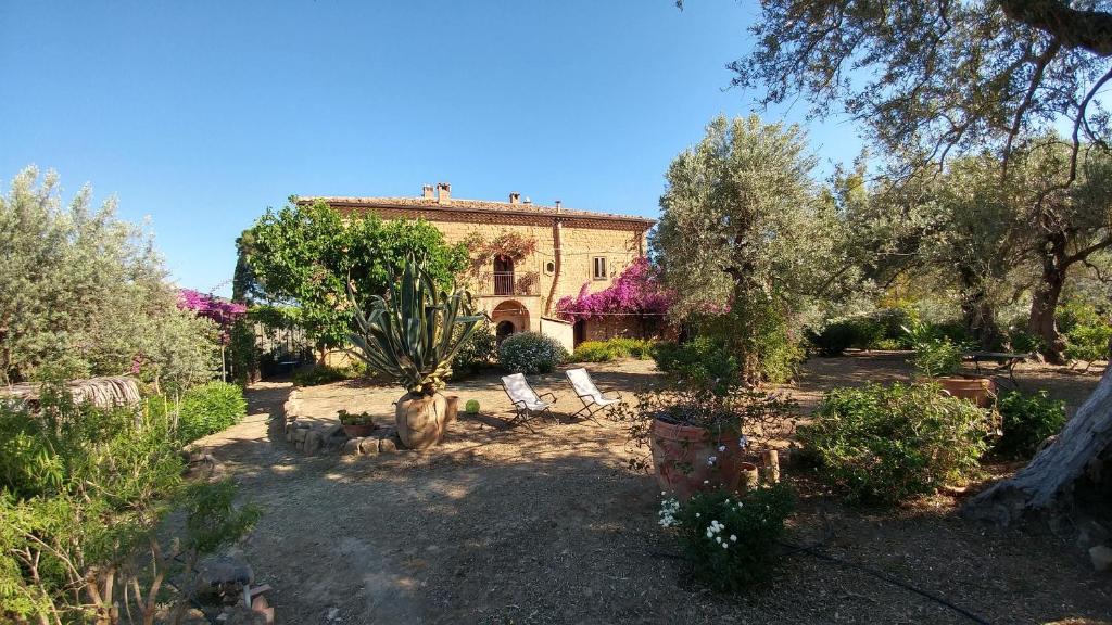 a house with trees and chairs in a yard at Casa Migliaca in Pettineo