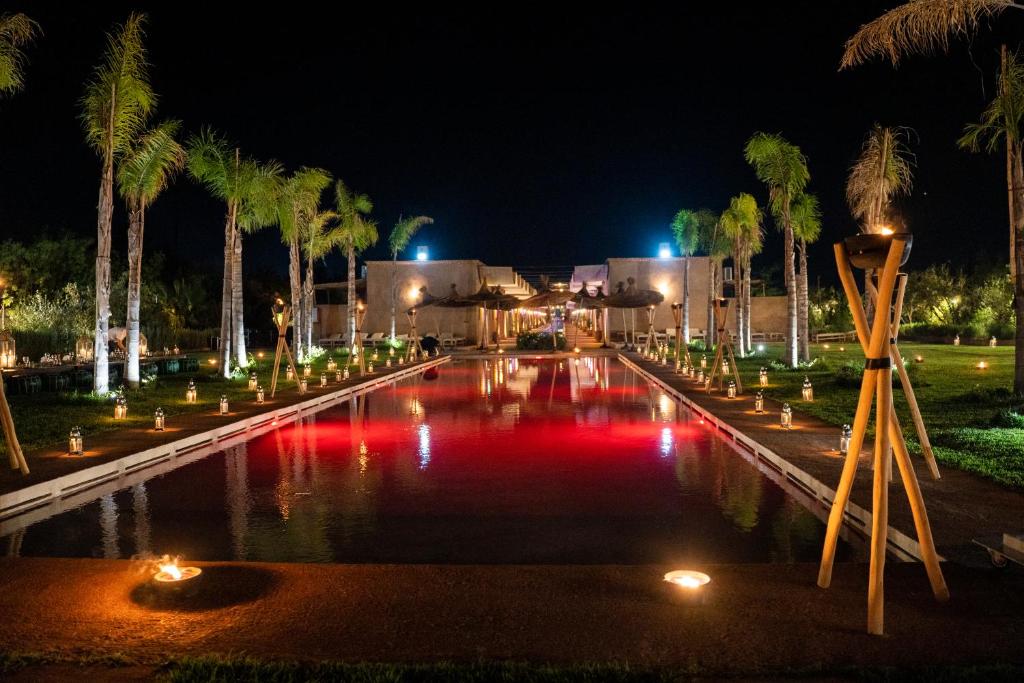 a pool with lights and palm trees at night at Al destino Resort Marrakech in Marrakech