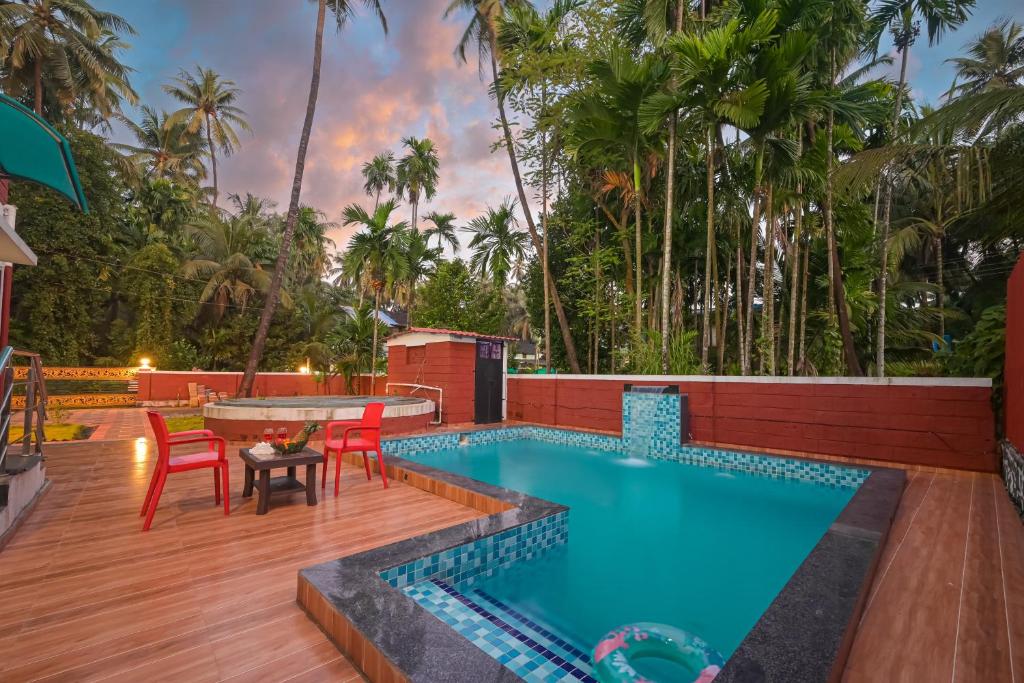 een zwembad op een terras met rode stoelen en een tafel bij ll EMPYREAN STAY ll REVDANDA BEACH ll in Revadanda